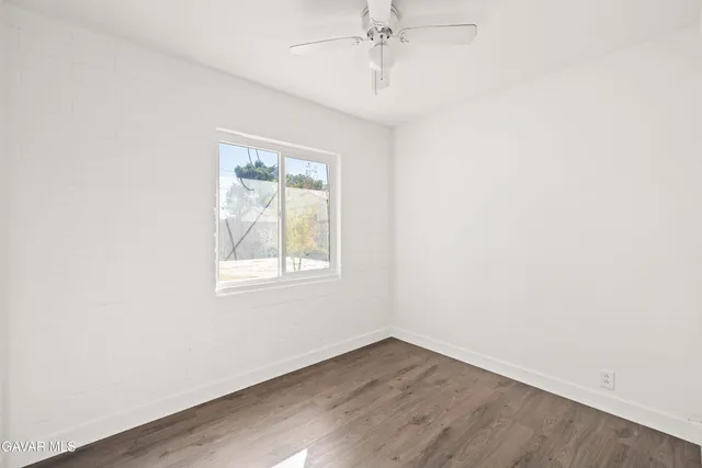 an empty room with a window and wooden floor