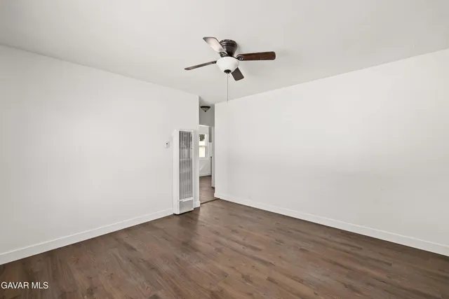 an empty room with wooden floor ceiling fan and window