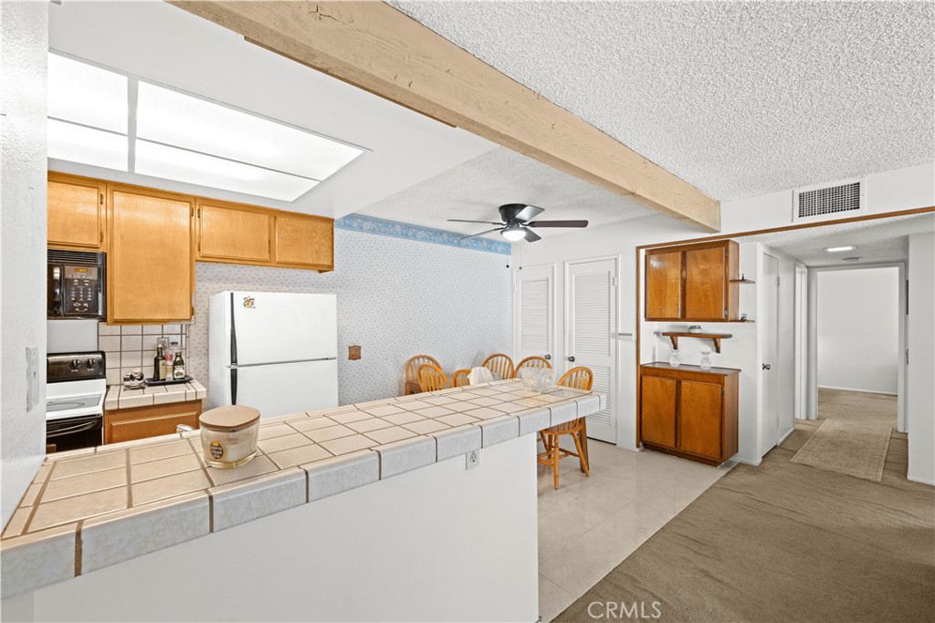 23 Country Mile Road Pomona, CA 91766 - Photo 4 of 36 Kitchen with tile counters, original 1983 cabinetry, pantry storage