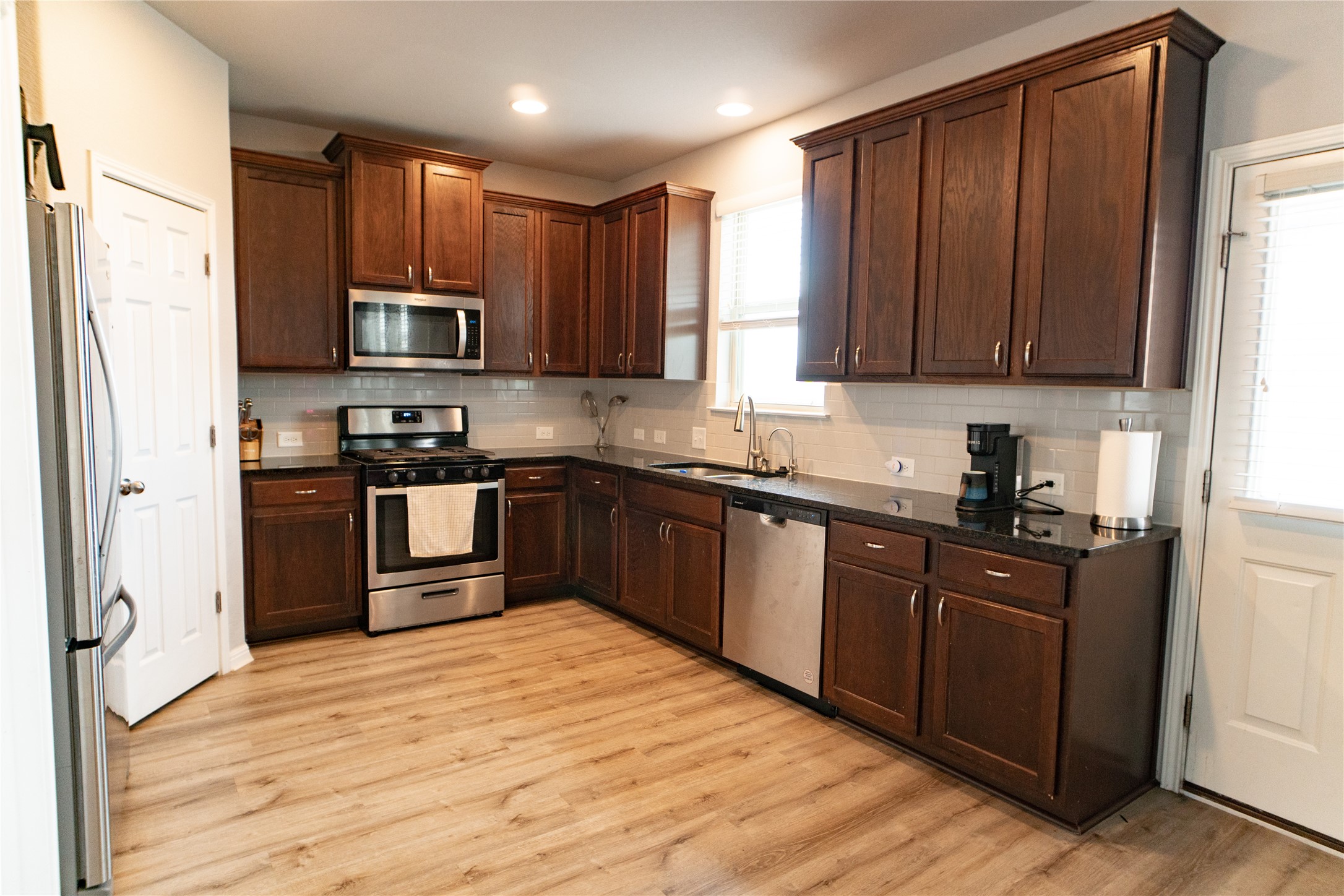 160 Shearwater Lane Leander, TX 78641 - Photo 7 of 24 a kitchen with stainless steel appliances granite countertop wooden cabinets a refrigerator a sink a stove and dishwasher with wooden floor