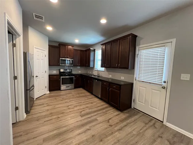 a kitchen with stainless steel appliances granite countertop a refrigerator and a stove top oven