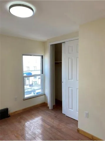 an empty room with wooden floor cabinet and windows