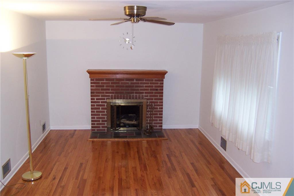 65 East Cliff Road Colonia, NJ 07067 - Photo 9 of 25 a view of a livingroom with wooden floor a fireplace and a window