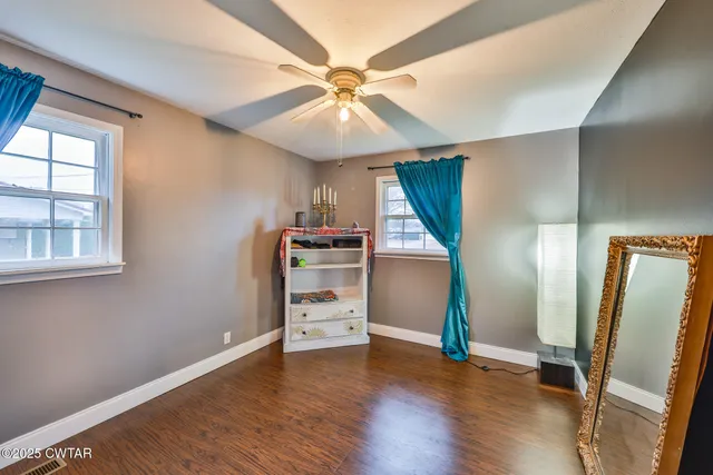 a view of a livingroom with wooden floor and a ceiling fan