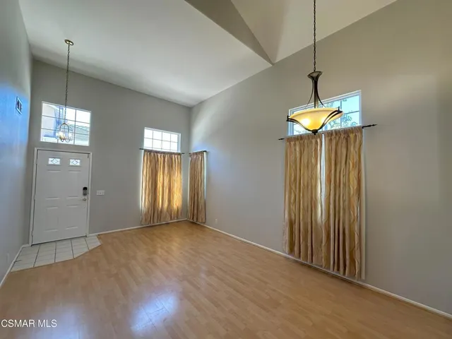 a view of an empty room with window and chandelier fan