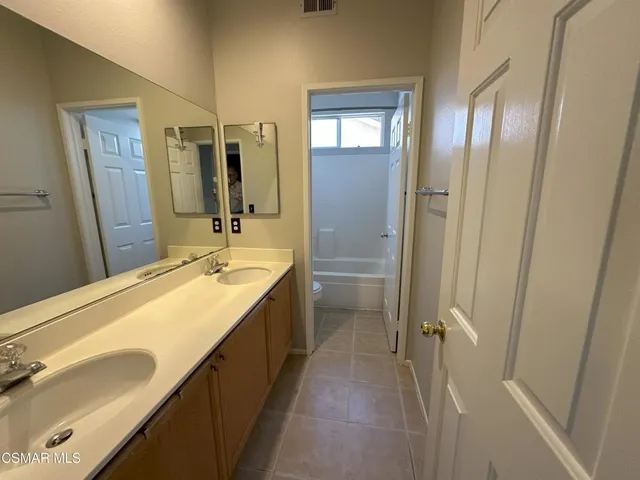 a spacious bathroom with a double vanity sink a mirror and a shower