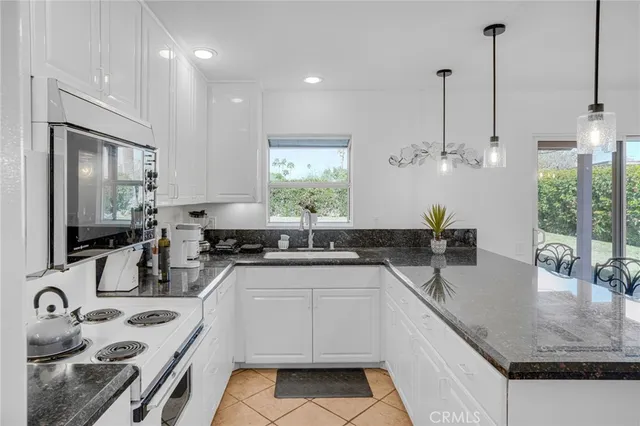 a kitchen with stainless steel appliances granite countertop a sink a stove a refrigerator and island with wooden floor