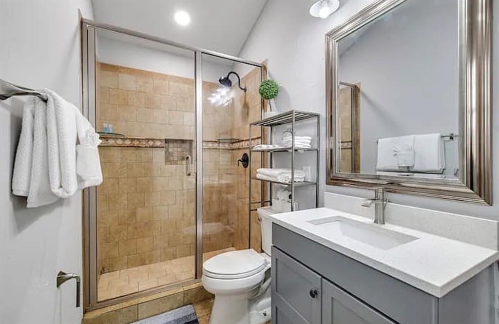 1718 Ripley Street Dallas, TX 75204 - Photo 14 of 33 Shower with tile surround and glass enclosure, modern vanity with white countertop, chrome faucet, and framed mirror