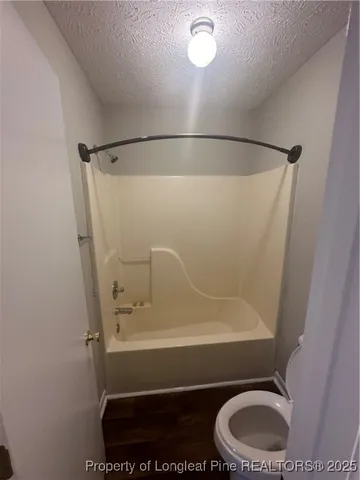 an empty room with wooden floor chandelier fan and windows