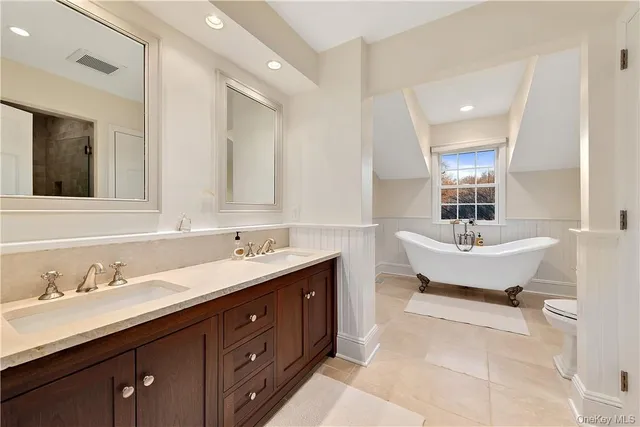 a bathroom with a tub double sink and mirror