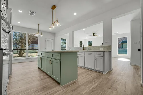 a kitchen with stainless steel appliances granite countertop wooden floors and white cabinets