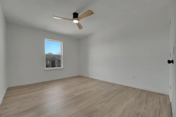 an empty room with wooden floor chandelier fan and windows