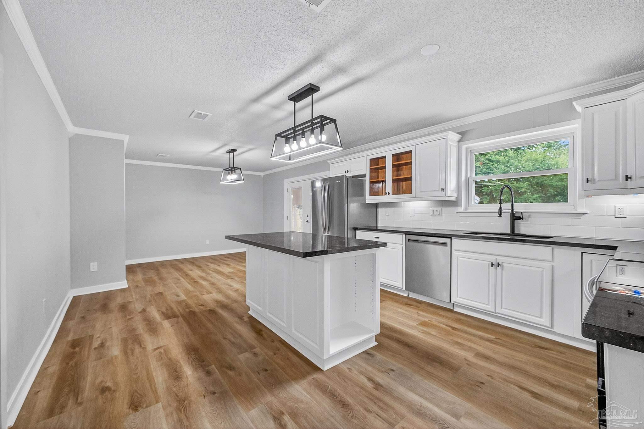 4673 Van Horn Road Milton, FL 32583 - Photo 22 of 53 a kitchen with stainless steel appliances granite countertop a sink dishwasher a stove and a dining table with wooden floor