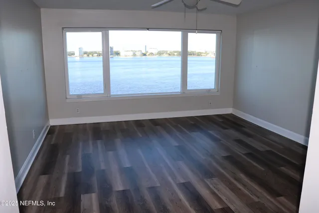 a view of an empty room with wooden floor and a window