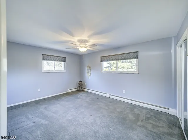 an empty room with windows and chandelier fan
