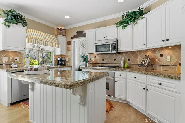 a kitchen with stainless steel appliances granite countertop a sink a stove a refrigerator and cabinets