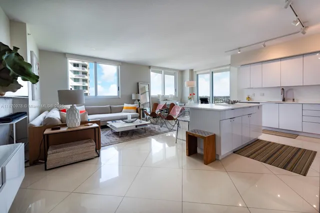 a living room with stainless steel appliances furniture a rug and a view of kitchen