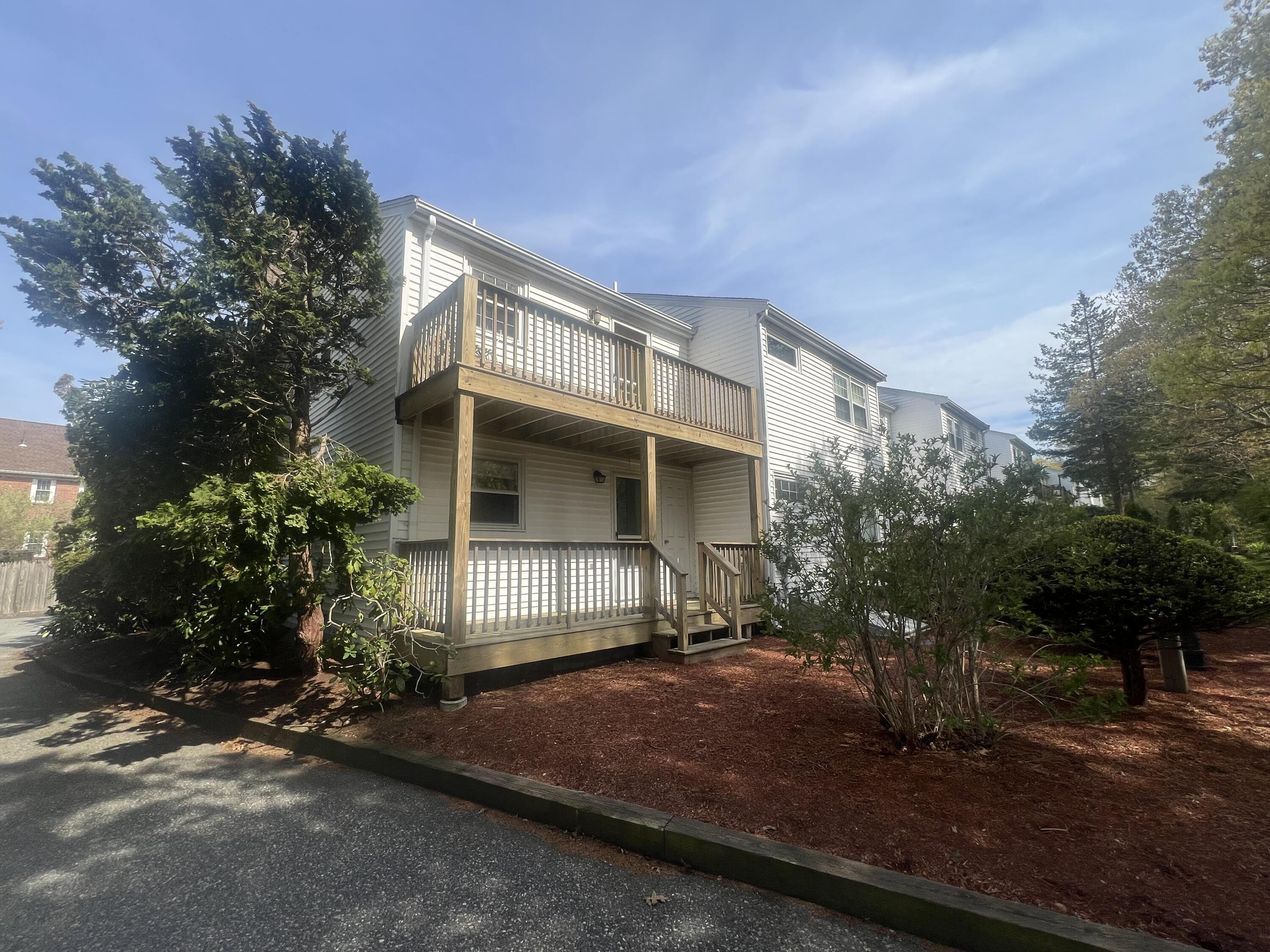 1431 Iyannough Road, Unit 1 Centerville, MA 02632 - Photo 24 of 28 a front view of a house with a yard and garage