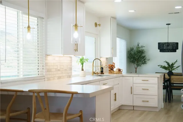 a kitchen with stainless steel appliances kitchen island granite countertop a refrigerator a sink a stove and white cabinets with wooden floor