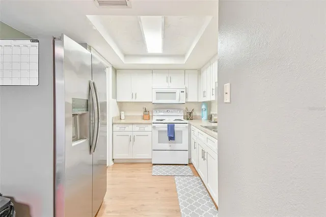 a kitchen with white cabinets and refrigerator