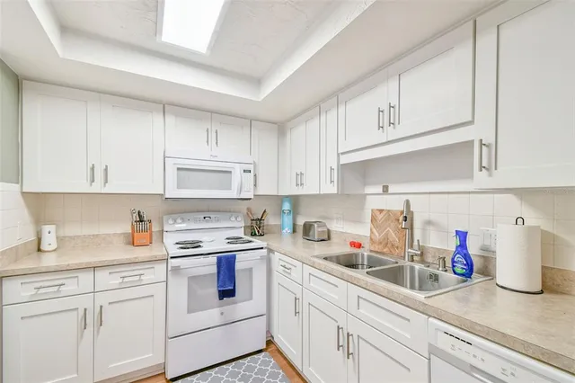 a kitchen with white cabinets and white appliances