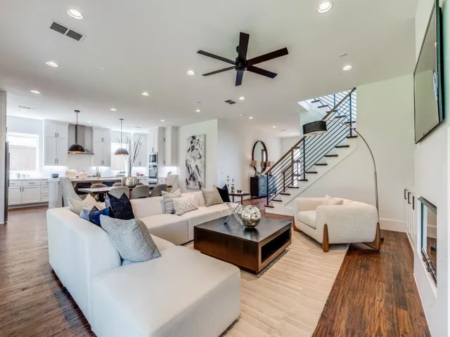 a living room with furniture kitchen view and a wooden floor
