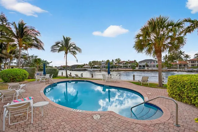 a view of a swimming pool with a lounge chair and palm trees