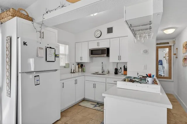 a kitchen with stainless steel appliances a refrigerator sink and white cabinets