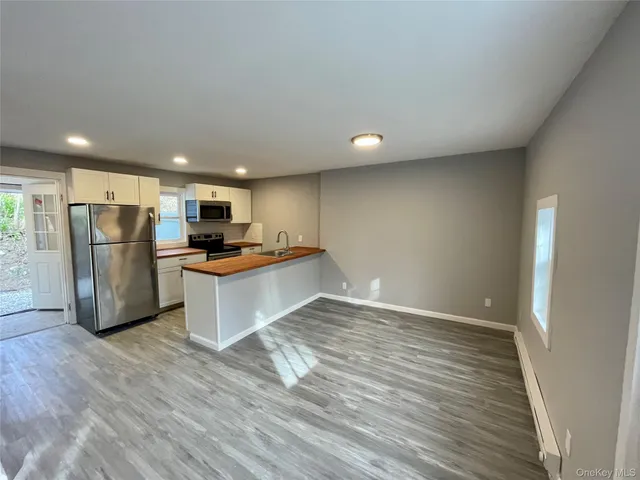 a view of kitchen with stainless steel appliances granite countertop a refrigerator and a stove top oven