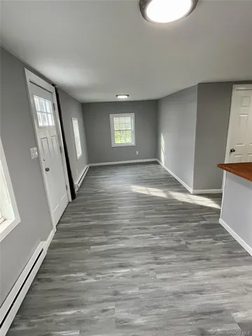 a view of an empty room with window and wooden floor