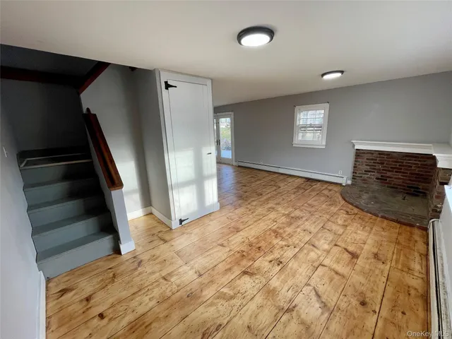 a view of an empty room with wooden floor and stairs