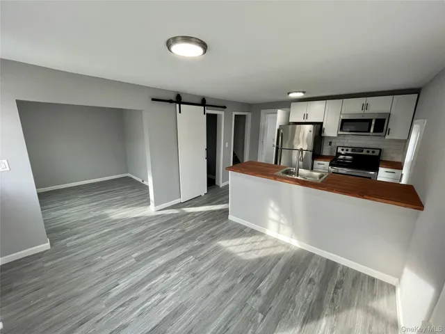 a view of a living room a kitchen with furniture and wooden floor