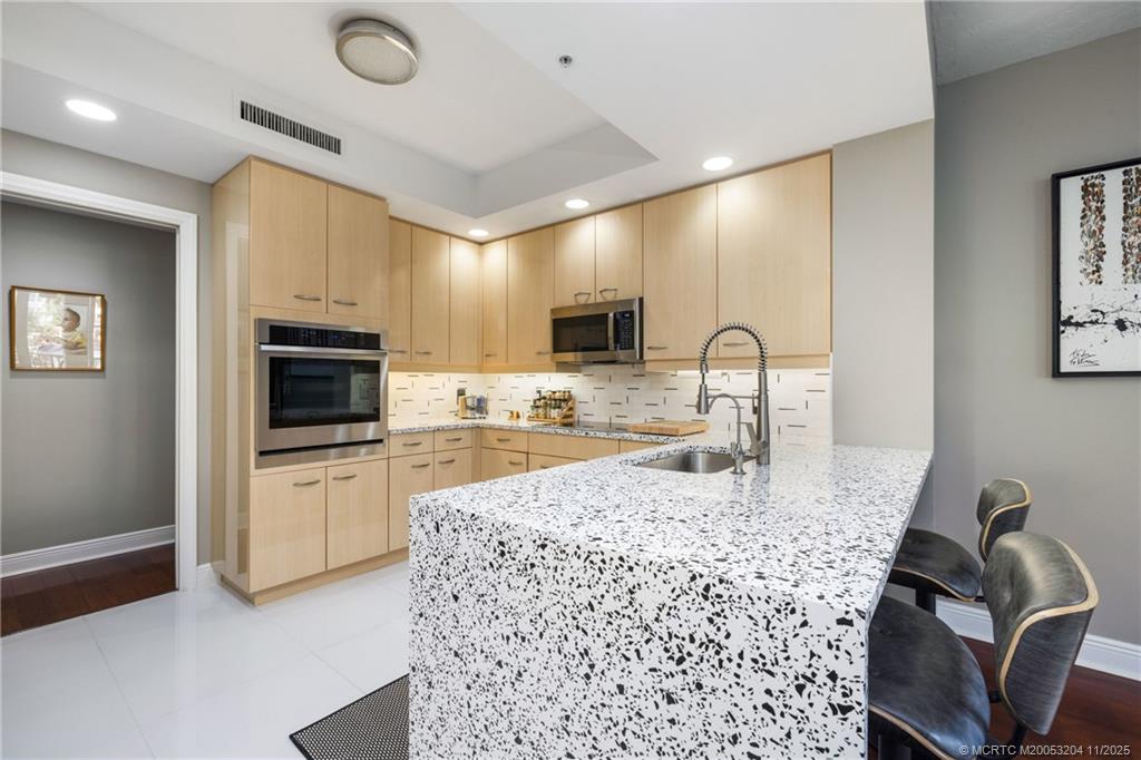 340 Highway 1, Unit 101 Jupiter, FL 33477 - Photo 15 of 42 a kitchen with kitchen island granite countertop a sink appliances cabinets and a counter top space