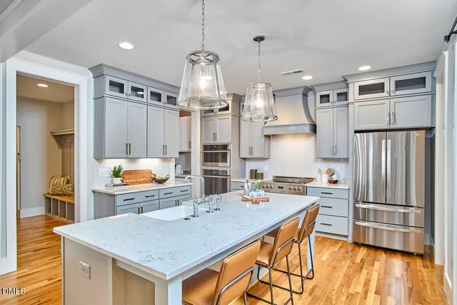 a kitchen with stainless steel appliances kitchen island granite countertop a table chairs in it and wooden floors
