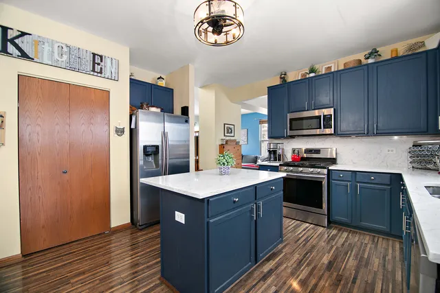 a kitchen with stainless steel appliances granite countertop a stove top oven a refrigerator a sink and dishwasher with wooden floor