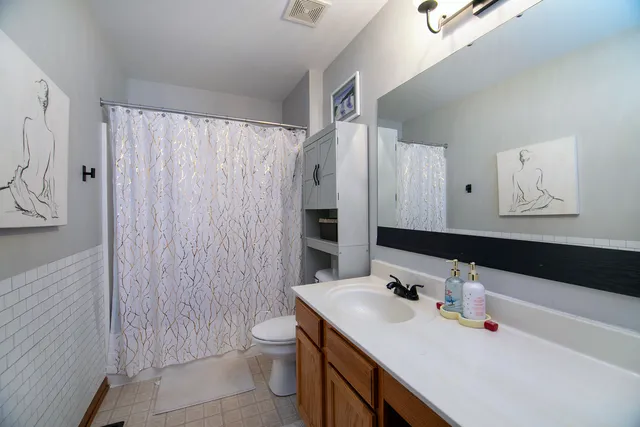 a bathroom with a sink toilet double vanity and shower