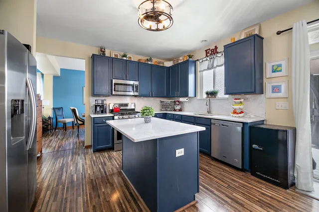 a kitchen with granite countertop a stove top oven a sink dishwasher and a refrigerator with wooden floor