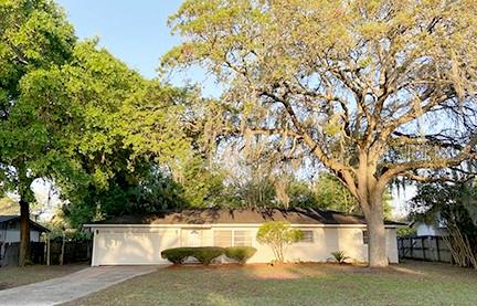 a view of a house with a yard and large tree