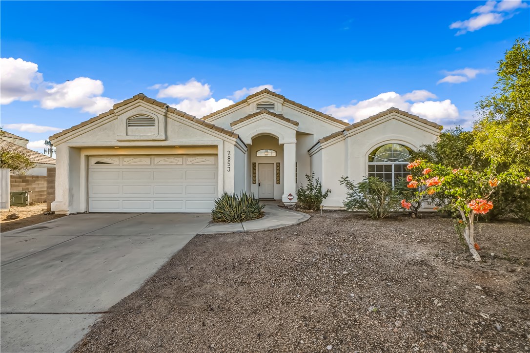 2853 Winchester Road Bullhead City, AZ 86442 - Photo 1 of 40 Stucco exterior with a tile roof, an integrated two-car garage, a concrete driveway, a covered entry, and an arched window accent