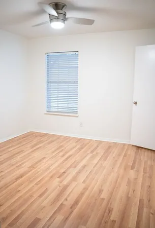 an empty room with wooden floor cabinet and windows