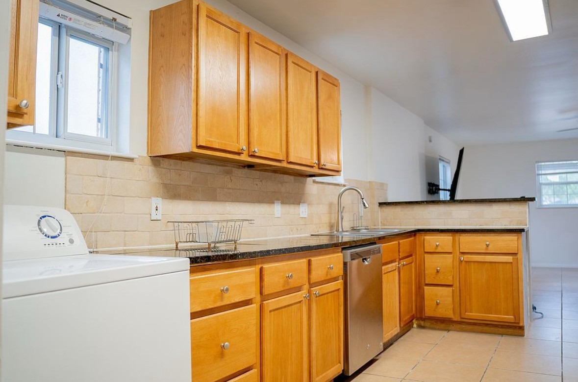 2841 San Gabriel Street Austin, TX 78705 - Photo 20 of 25 Kitchen featuring washer / dryer, stainless steel dishwasher, light tile patterned floors, a peninsula, and wood finish cabinetry