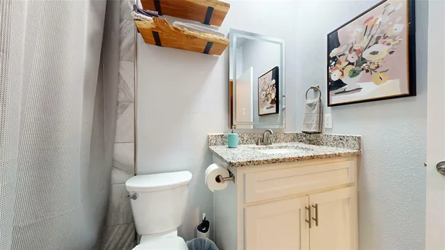 a bathroom with a granite countertop toilet a sink and a mirror
