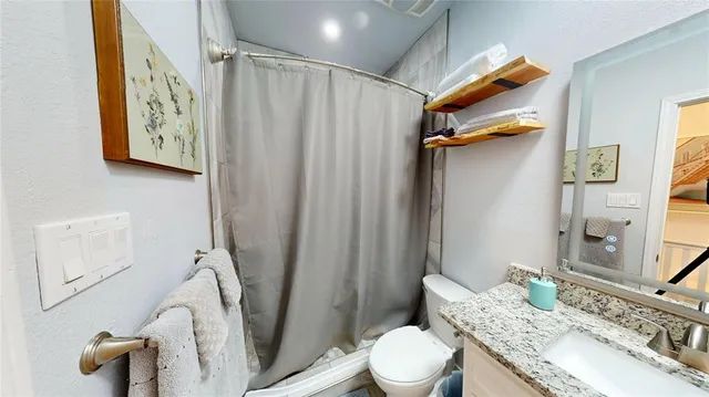 a bathroom with a granite countertop sink toilet and shower