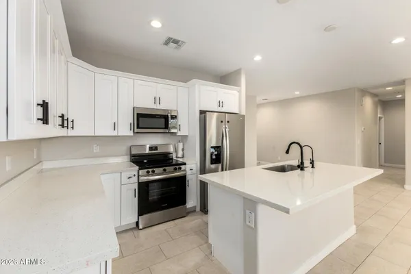 a kitchen with stainless steel appliances granite countertop a sink a stove a microwave a refrigerator a sink and white cabinets