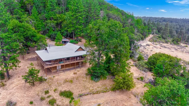 an aerial view of a house with a yard and tree s
