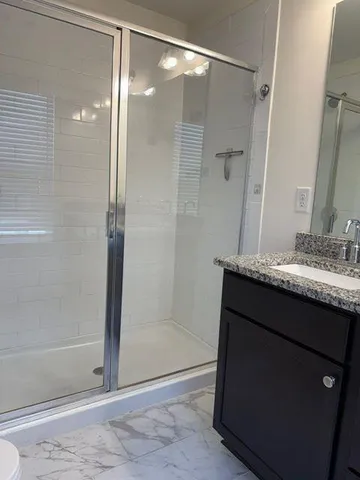 a bathroom with a granite countertop shower sink and mirror