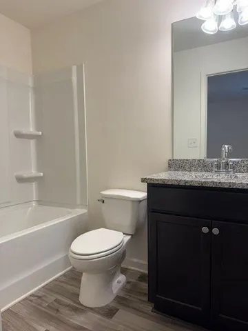 a bathroom with a granite countertop toilet a sink and a bathtub