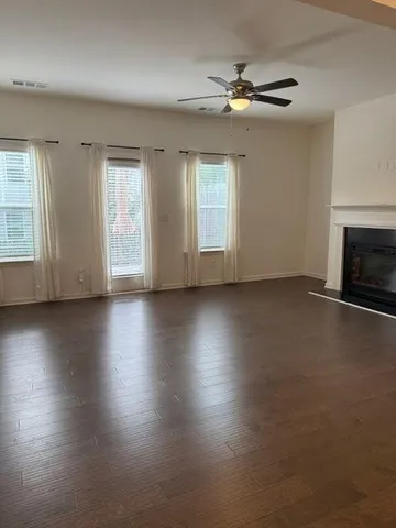 an empty room with wooden floor fireplace and windows