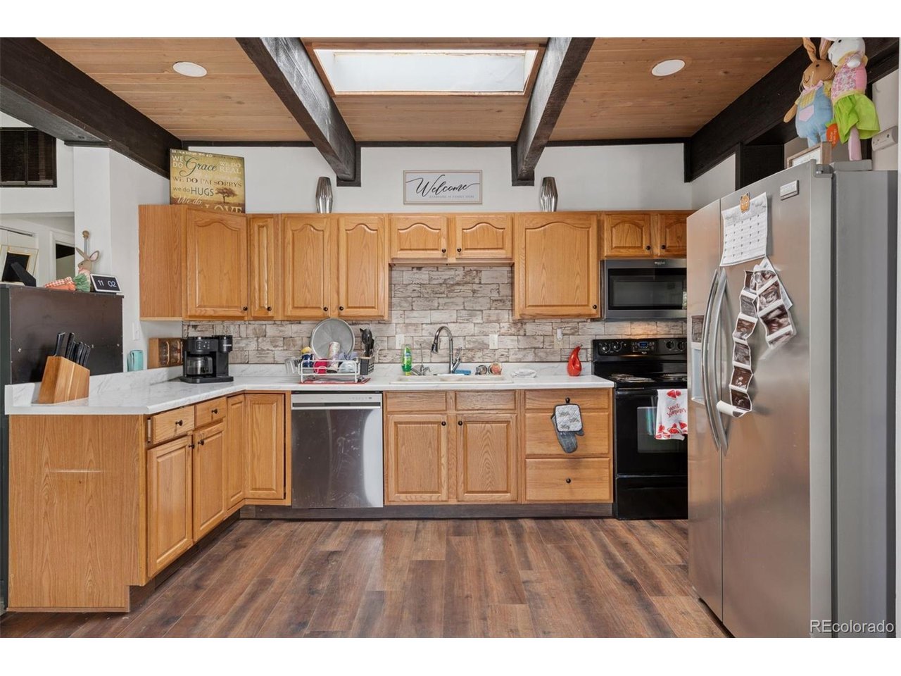 16880 Old Pueblo Road Fountain, CO 80817 - Photo 12 of 49 Kitchen featuring wood cabinetry, stone-like tile backsplash, stainless steel appliances, and vaulted ceiling with exposed beams and skylight