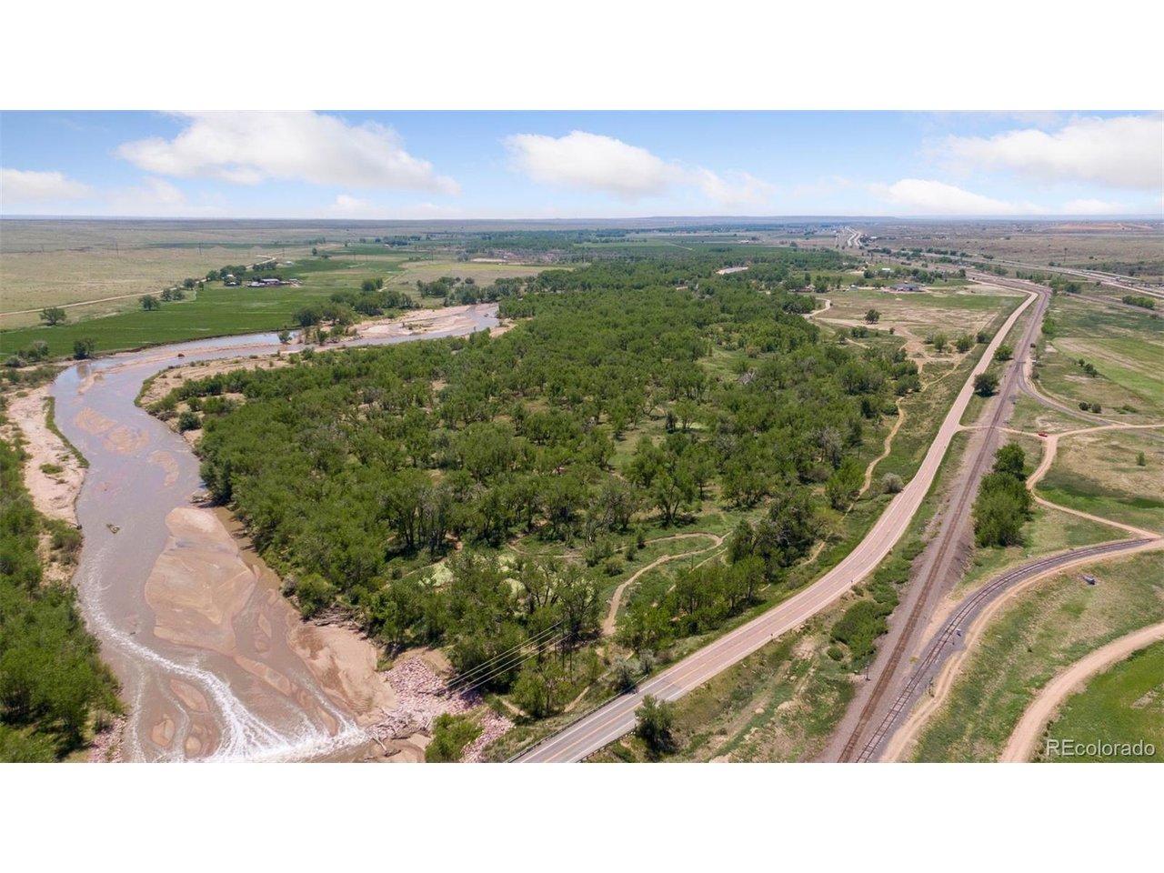 16880 Old Pueblo Road Fountain, CO 80817 - Photo 2 of 49 Aerial view highlighting Fountain Creek frontage, mature cottonwood corridors, and adjacent roadway access, emphasizing the property's natural setting and connectivity within the surrounding landscape.